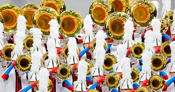 Personas con uniformes blancos y rojos que tocan brillantes instrumentos de metal