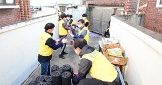 People wearing yellow jackets passing briquettes down a human assembly line