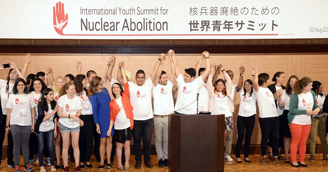 A group of youth pose for a photo beneath a banner.