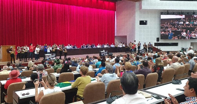 Personas en una gran sala de conferencias frente a un escenario.