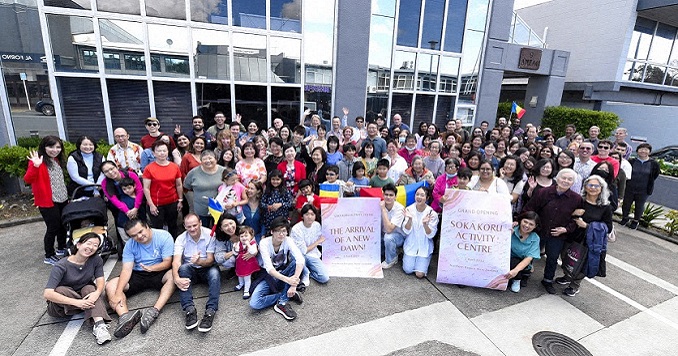 A large group of people posing for a photo outside a multistory building