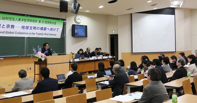 Seated participants in a conference hall listening to the speaker at the podium