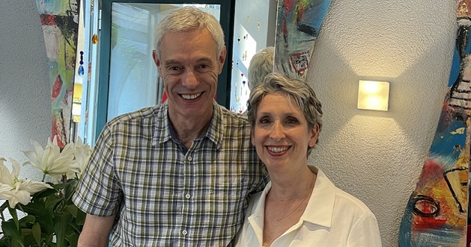 Dominique Kohli posing with his wife in his salon in front of colorfully framed mirrors