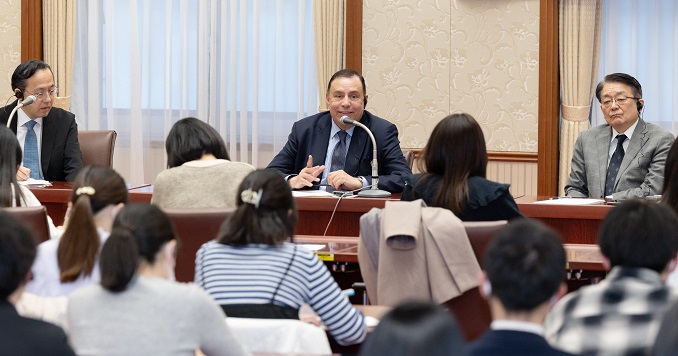 A man speaking in front of an audience in a conference room.