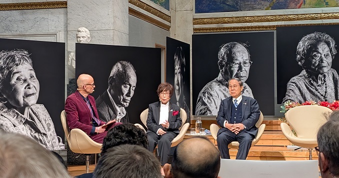 A panel of three people in front of large images of hibakusha.