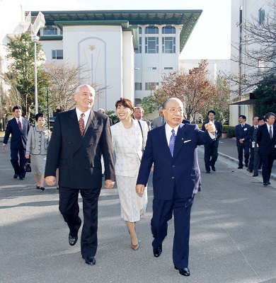 Two men in suits and a woman in a white suit walking side by side outside