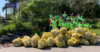 Group of young people in high-visibility vests with lots of yellow garbage bags.