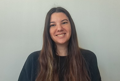 Young woman with long, brown hair smiling at the camera.