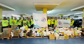 Group of young people in high-visibility vests with boxes and bags of donated food.