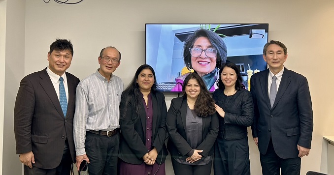 Six people standing in front of screen with one person on.