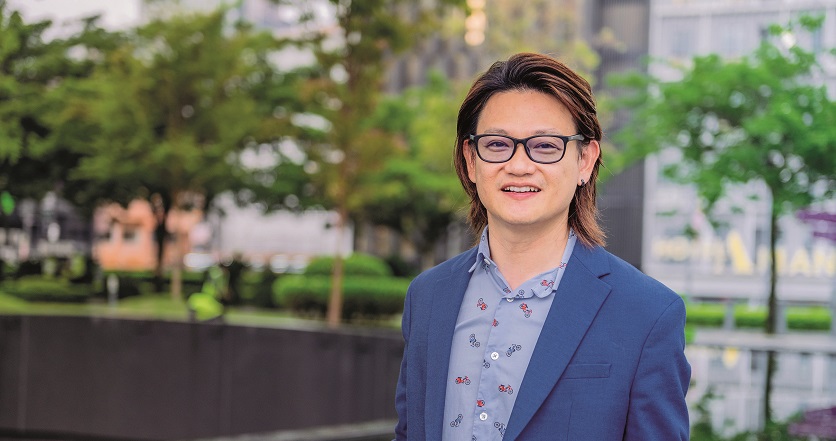 一位穿西装、戴眼镜的男士面对镜头微笑。