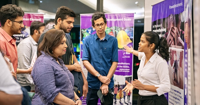 Exhibition visitors listening to a woman explaining one of the panels.