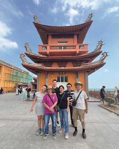 Szi Hean and her family posing outside a large, orange pagoda-like building