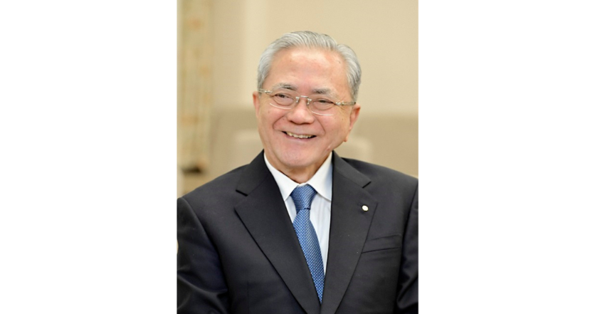 A man dressed formally smiling and looking slightly to the side.