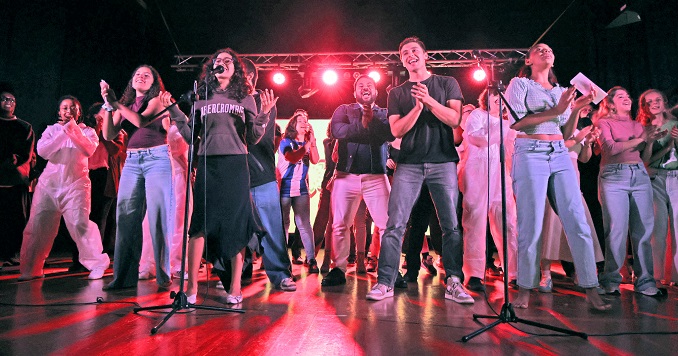 Young people standing onstage and singing together.