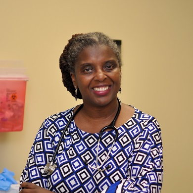 婦人站在室內黃棕色牆面前的特寫照片。