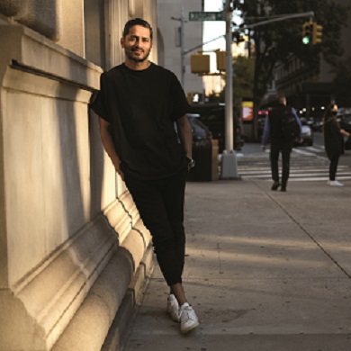 Mayur leaning against a building on a New York city street