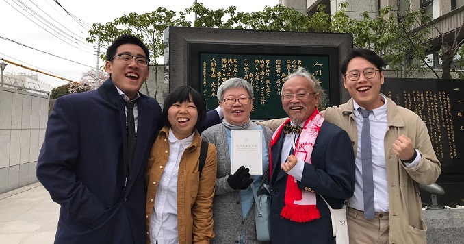 Five family members pose for a commemorative photograph outside a building in Japan
