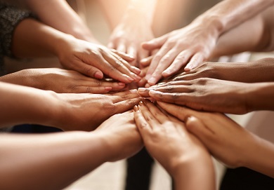 Diverse hands come together in a circle, symbolizing unity.