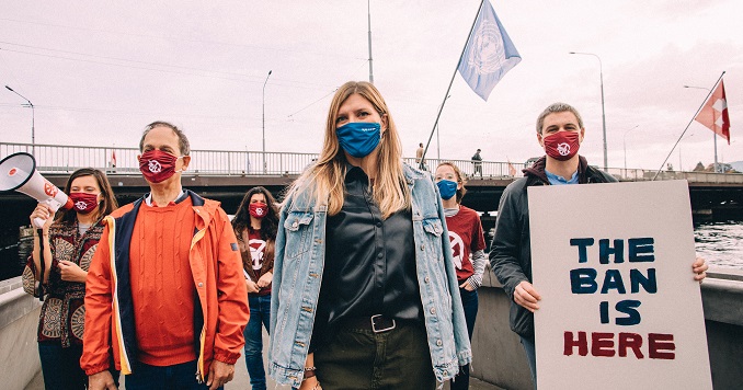 Un grupo de personas, entre las que se encuentra la Sra. Fihn, se coloca en un paseo marítimo con un cartel que dice “The ban is here”