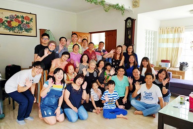 Group photo of around 30 smiling men, women and children