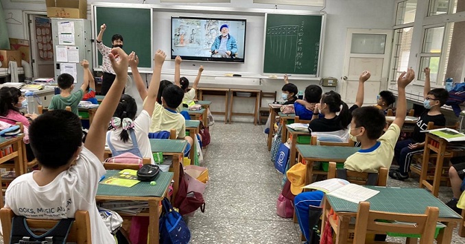 Elementary students raising hands during a mobile art museum presentation