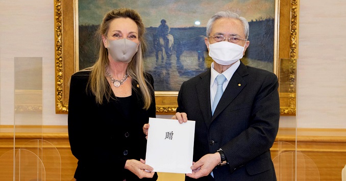 Dos personas con mascarillas frente a una pintura