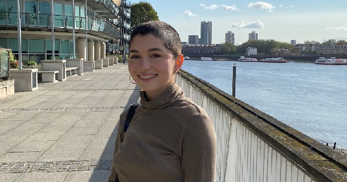 Una mujer joven sonriente de pie en un paseo marítimo